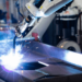 Industrieroboter beim automatisierten Schweißvorgang an Metallrahmen